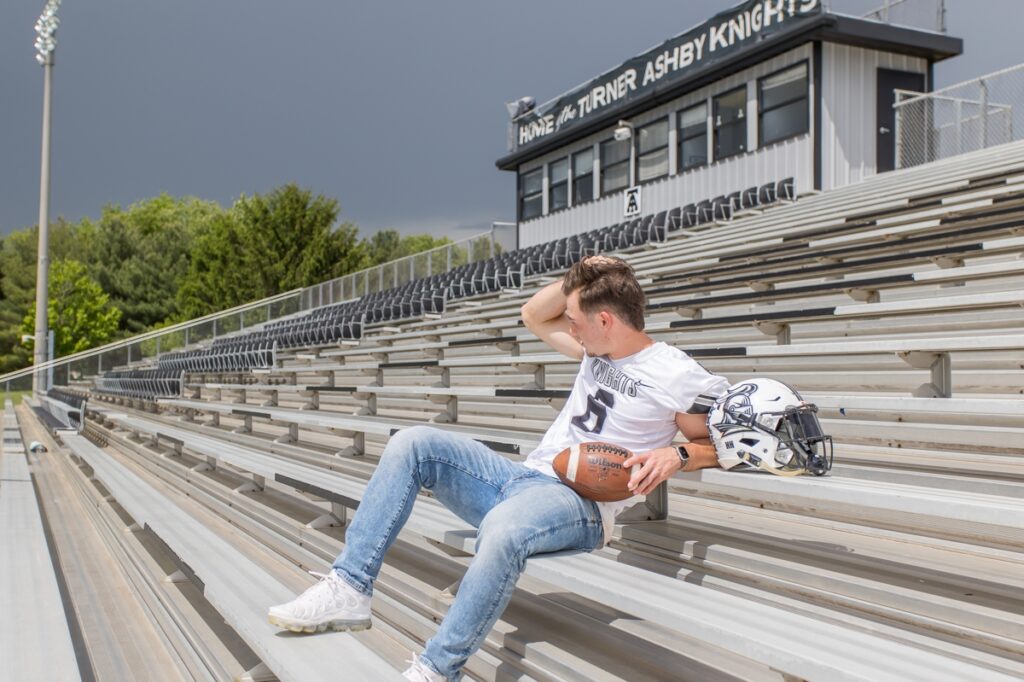 Sam Shickel posing on the bleachers of his high school's football stadium during his rainy senior photoshoot