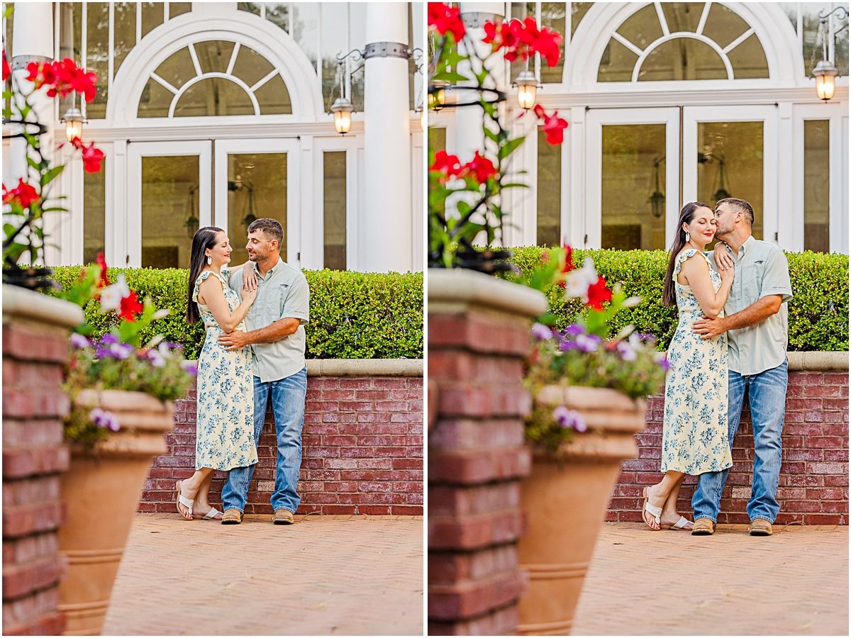 Mary and Daniel by a pair of white double doors framed by red flowers. Engagement photography done in Virginia